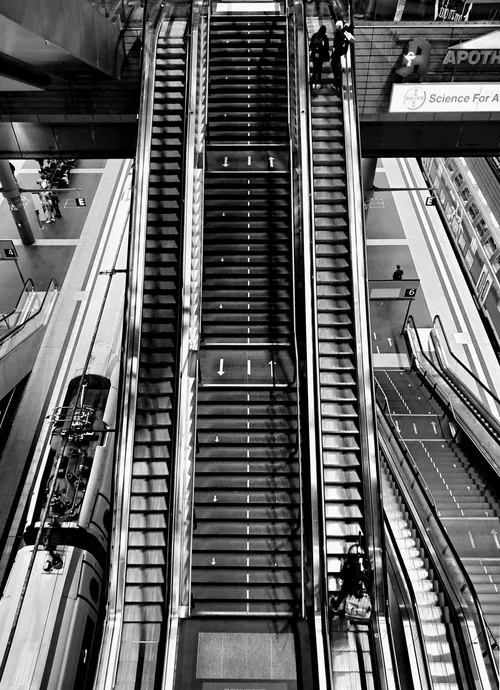 Escalator shaft seen head-on, its steel treads and rails running in parallel