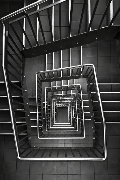 Square stairwell from above, flights receding toward a small floor