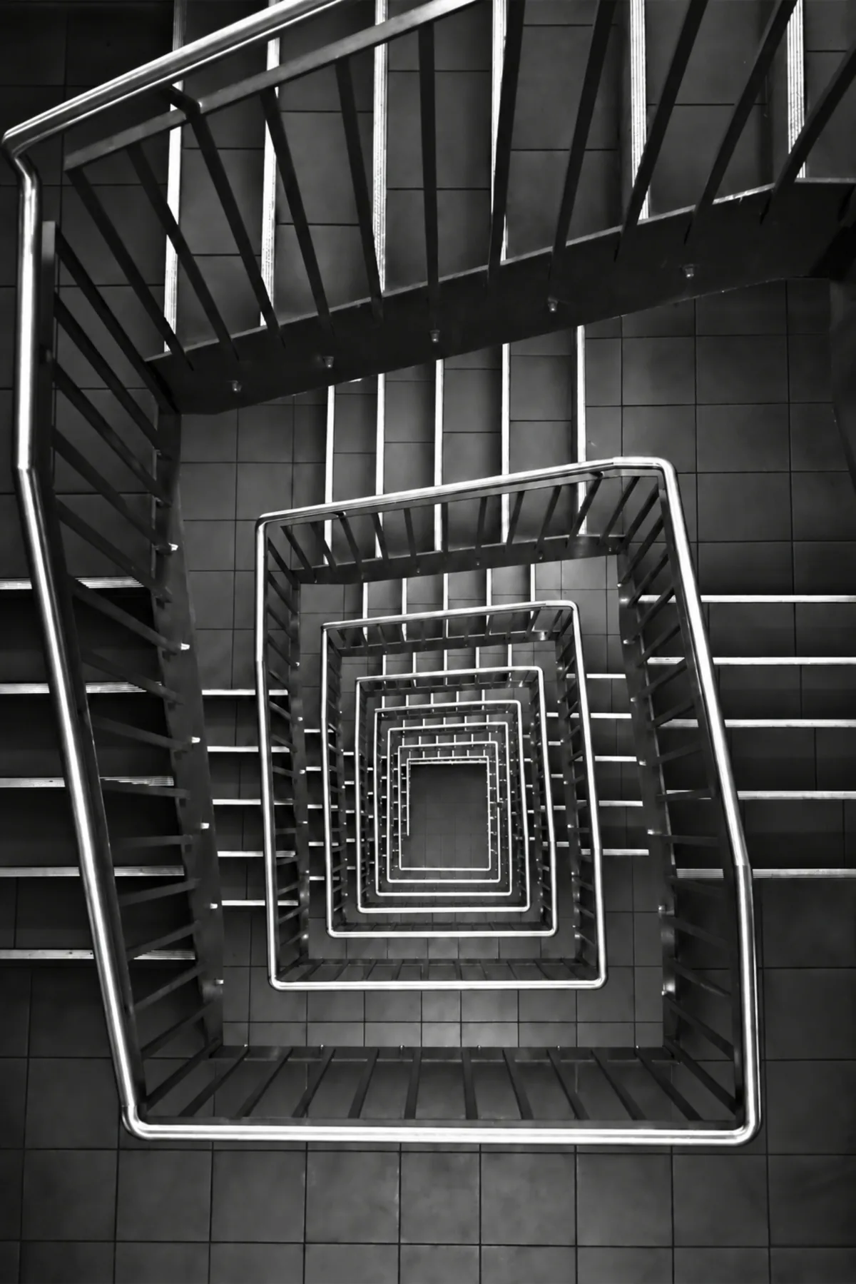 Square stairwell from above, flights receding toward a small floor