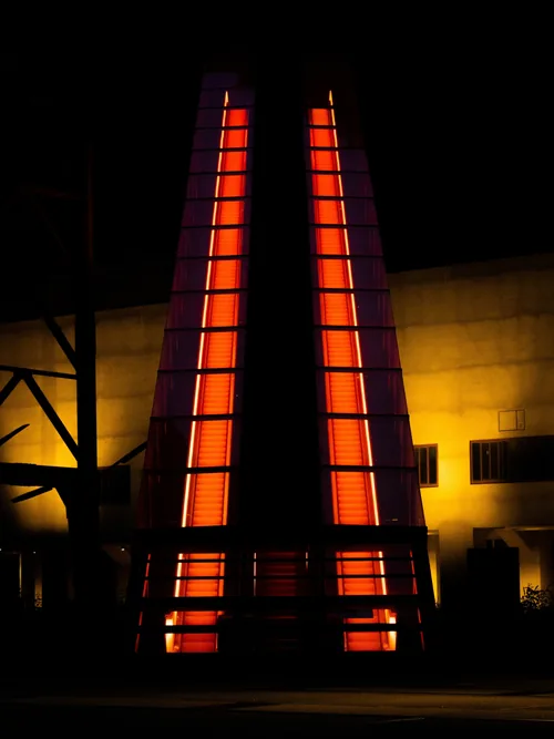 Glowing orange stair tower at night against a dark façade