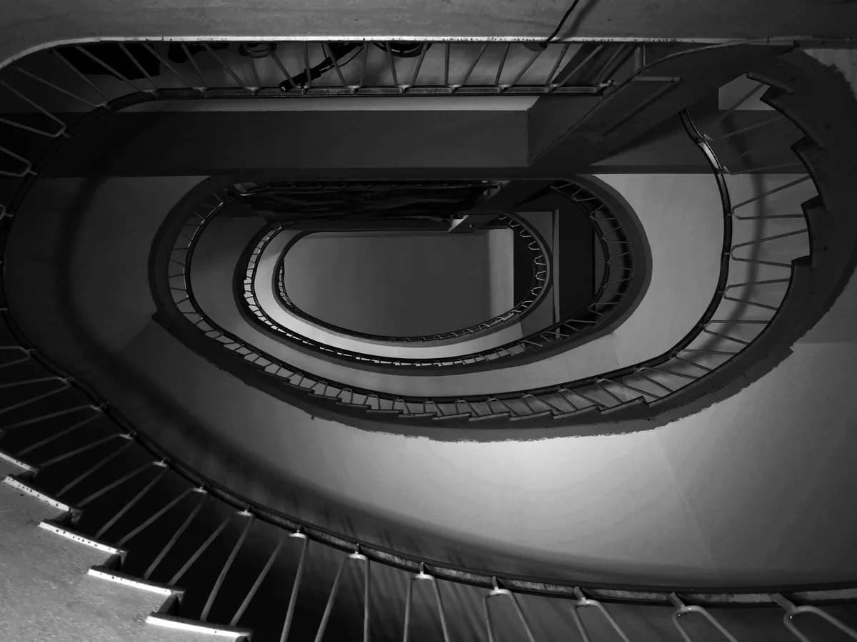 Elliptical stair from above, dark treads ringing a pale void