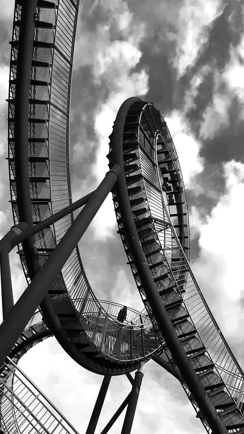 Looping steel walkway sculpture against a clouded sky