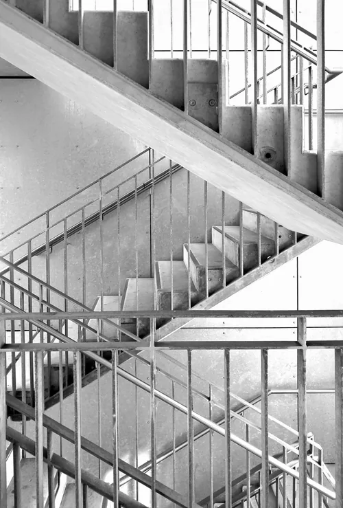 Steel stair flights crossing behind a glass and grid façade
