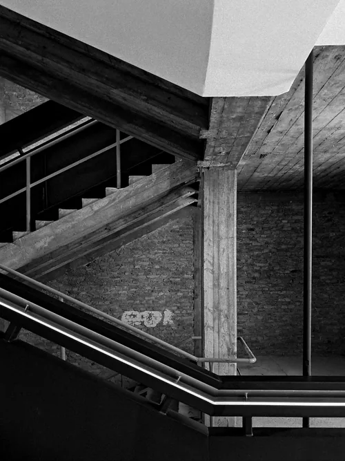 Concrete stair and railings beside a brick wall, seen at an angle
