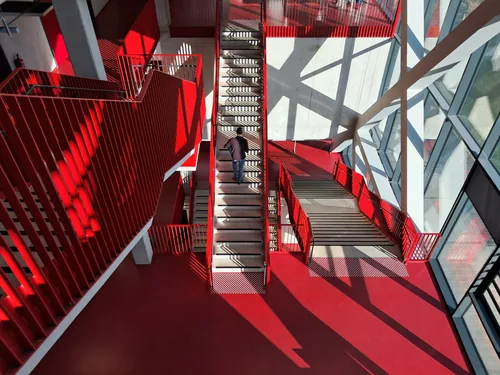 Red stair hall cut by diagonal glass panes and shadows