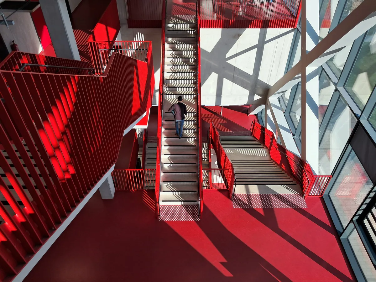 Red stair hall cut by diagonal glass panes and shadows