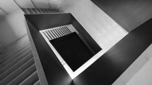 Rectangular stairwell from above, a white flight dropping into black