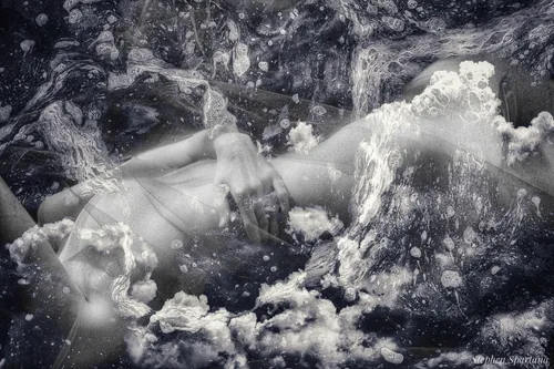 Floating on a Cloud by Stephen Spartana. A black-and-white reclining body merges with billowing clouds and water spray.