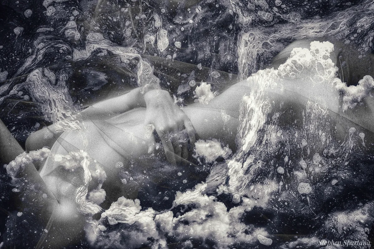Floating on a Cloud by Stephen Spartana. A black-and-white reclining body merges with billowing clouds and water spray.