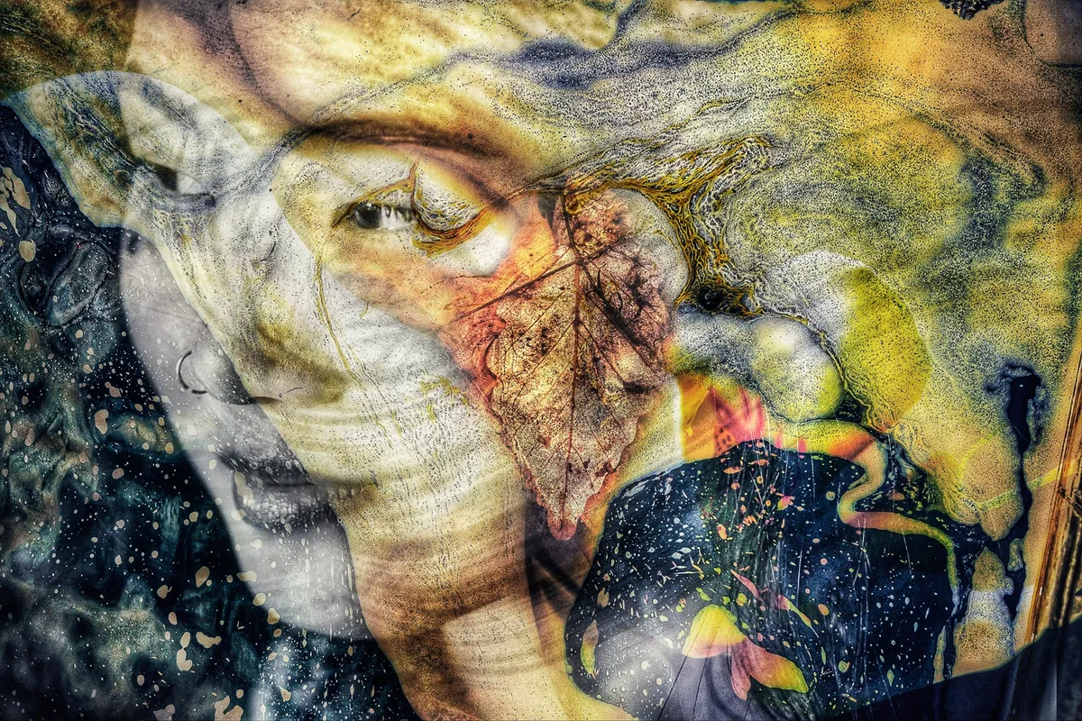 Masquerade by Stephen Spartana. A face half-hidden behind an autumn leaf and a starry dark shape, in yellow, ochre and deep blue.