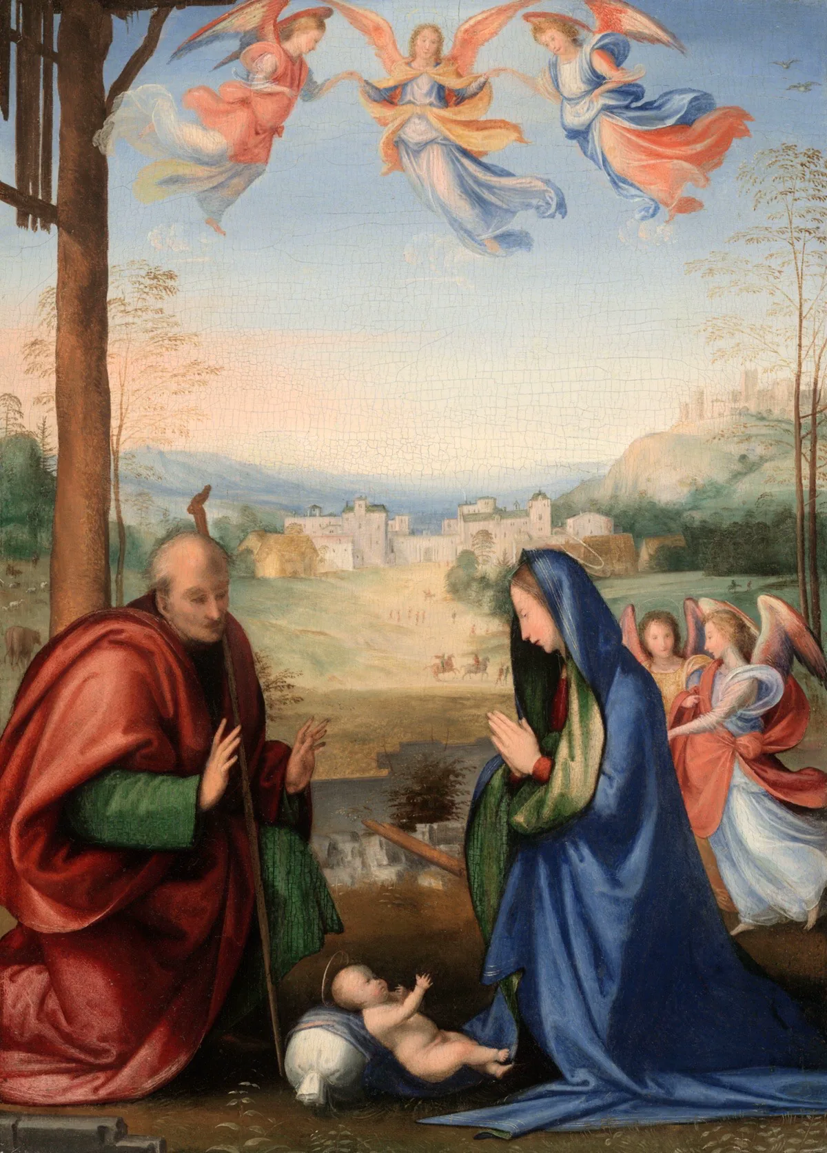 A light-skinned man in red and woman in blue sit with an infant between them, angels beside and above them, a small town in the background.