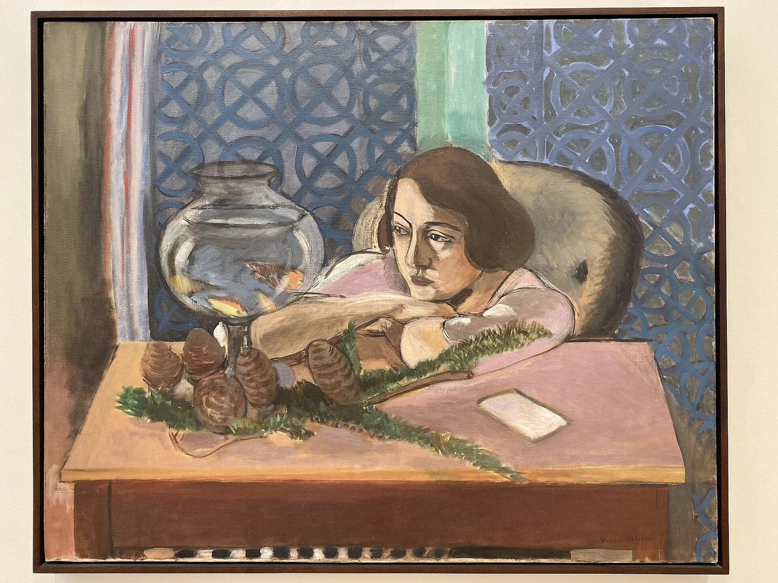 Painting of woman, arms crossed on brown desk, staring at goldfish.