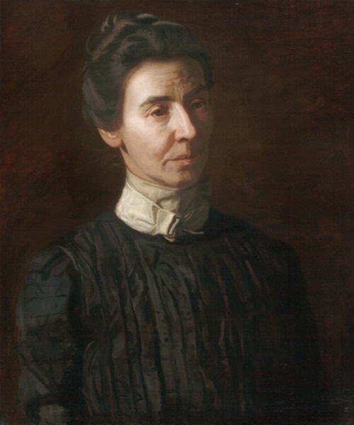 Dark portrait of an older light-skinned women with dark hair in a black dress and white collar, her hair pinned up. Her face is in partial shadow.