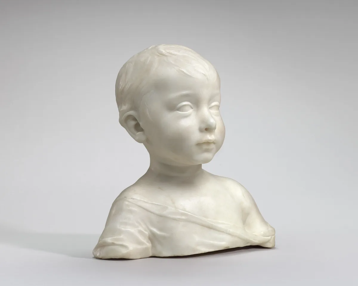 This free-standing, white marble bust shows the head, shoulders, and upper chest of a young boy.