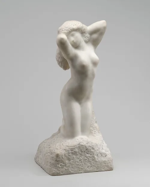 A woman kneeling with both arms raised by her head is carved from white marble in this freestanding sculpture.