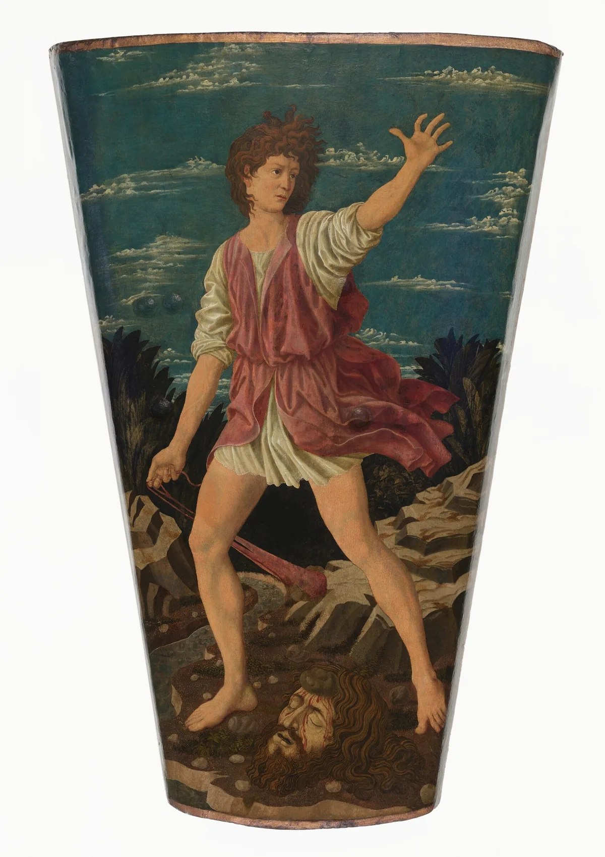 This shield-shaped painting shows a young man with pale, peachy skin and curling brown hair standing astride the severed head of a man with dark hair and tanned skin.