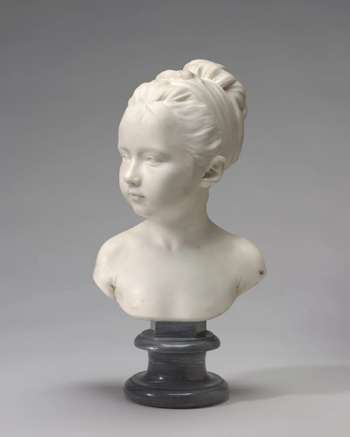 The sculpture is a bust depicting a young girl with delicate features.