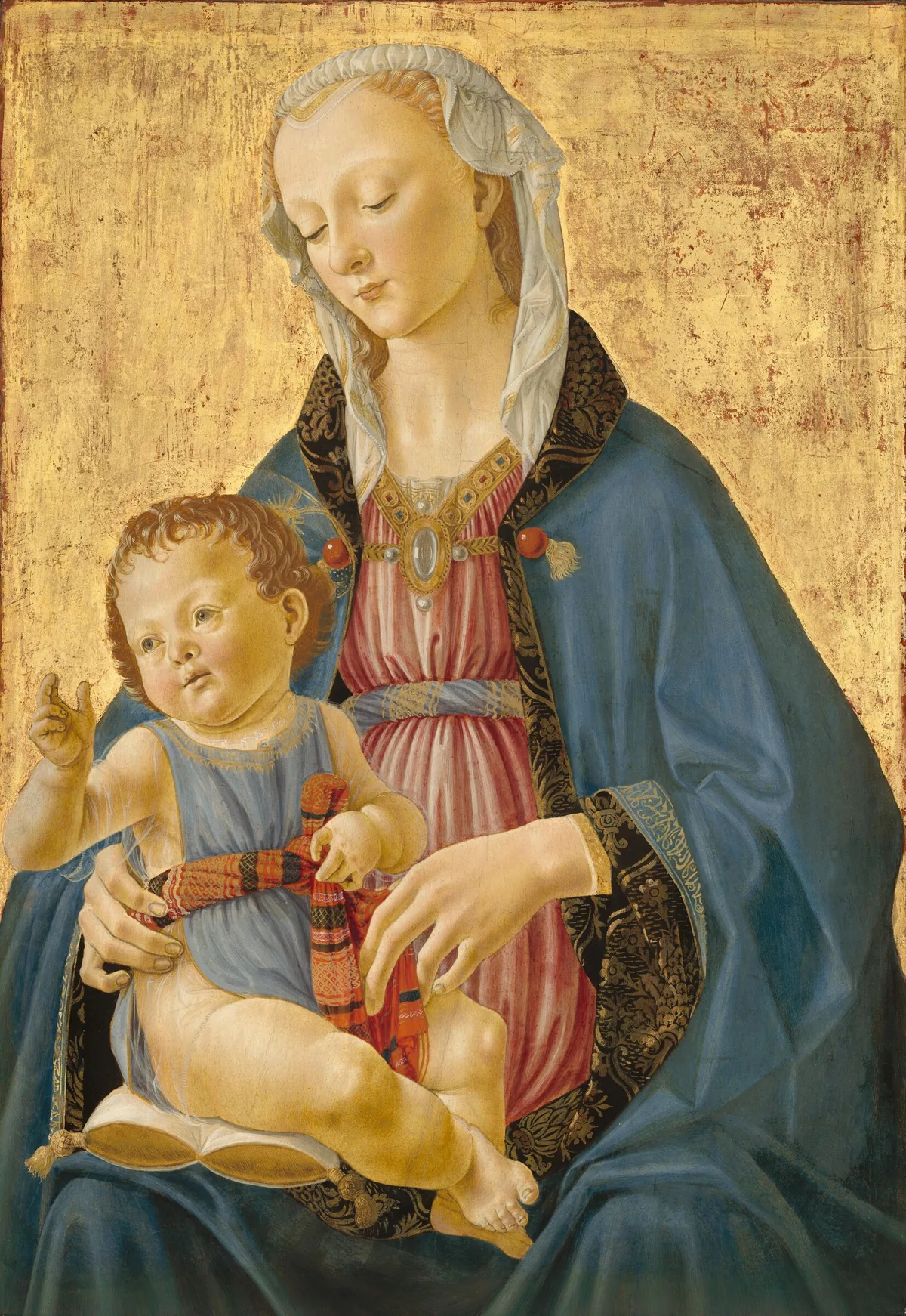 Against a gold background, a blond woman is shown from the lap up, facing us as she holds and looks down at a plump baby sitting on a gold and white pillow on her lap in this vertical painting.