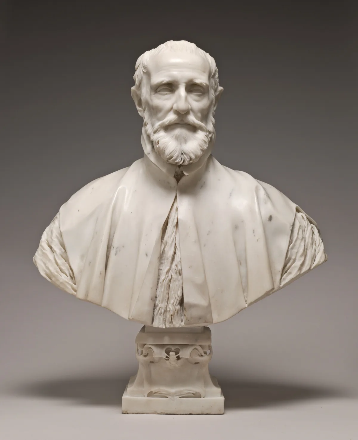 This free-standing, white marble sculpture shows the head, shoulders, and upper chest of a balding, bearded man.