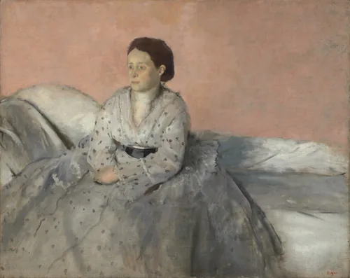Shown from about the ankles up, a woman with ashen, pale skin, wearing a full, silvery-white dress with gray dots, sits on a low-backed white sofa against a pale peach background in this horizontal portrait painting.
