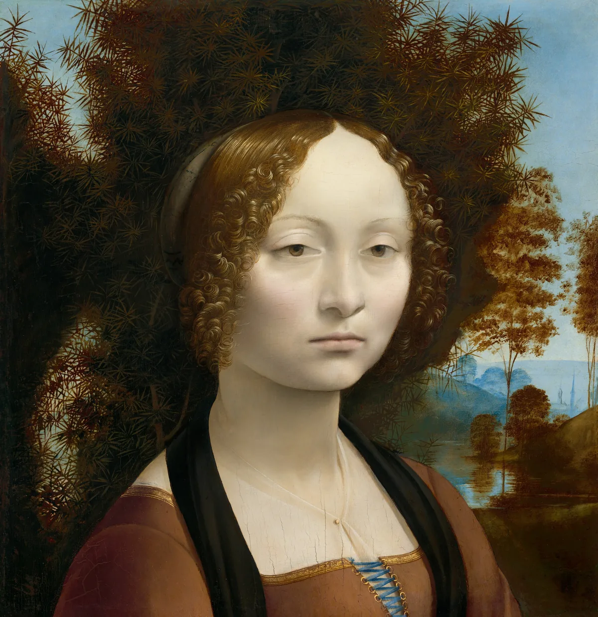 This square portrait shows the head and shoulders of a young woman in front of a spiky bush that fills much of the background except for a landscape view that extends into the deep distance to our right.