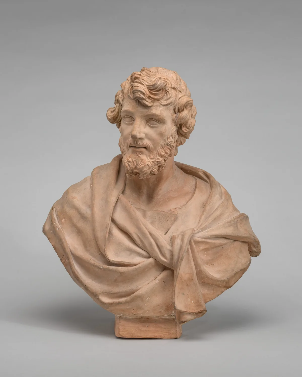 The sculpture is a bust of a bearded man with curly hair, draped in a garment knotted at the front.