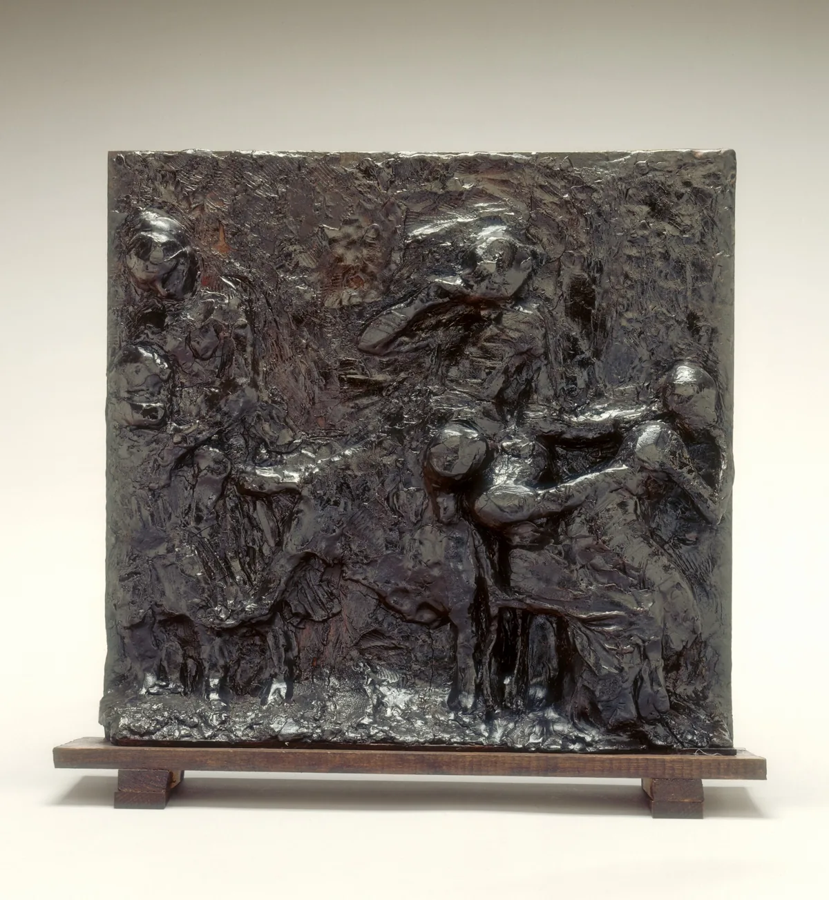The image shows a relief panel with multiple human figures in dynamic poses.
