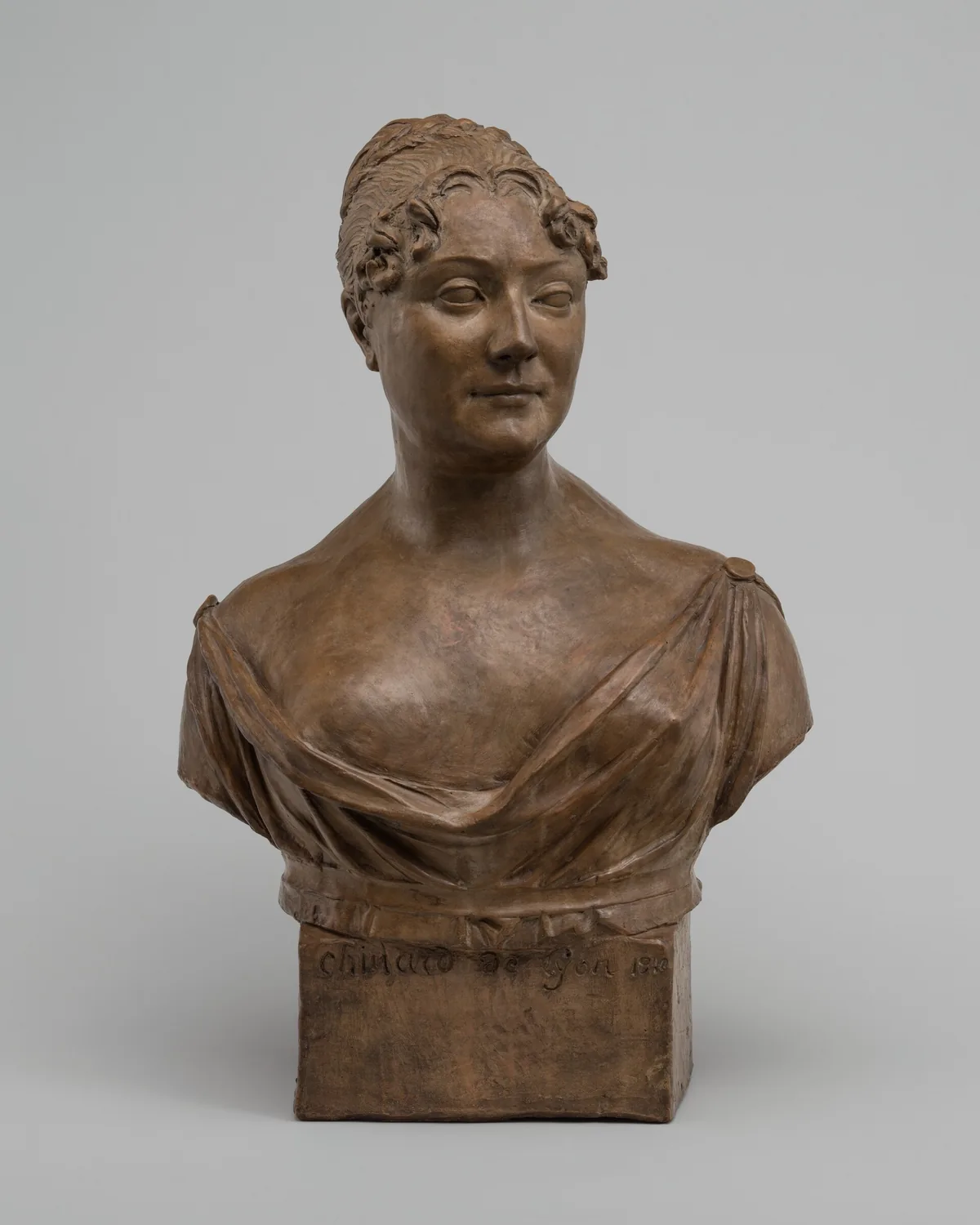 The sculpture is a bust of a woman, capturing her from the chest up.
