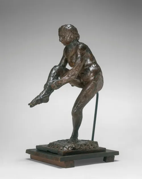 The sculpture shows a figure tying a ribbon around their toes, balanced on one foot.