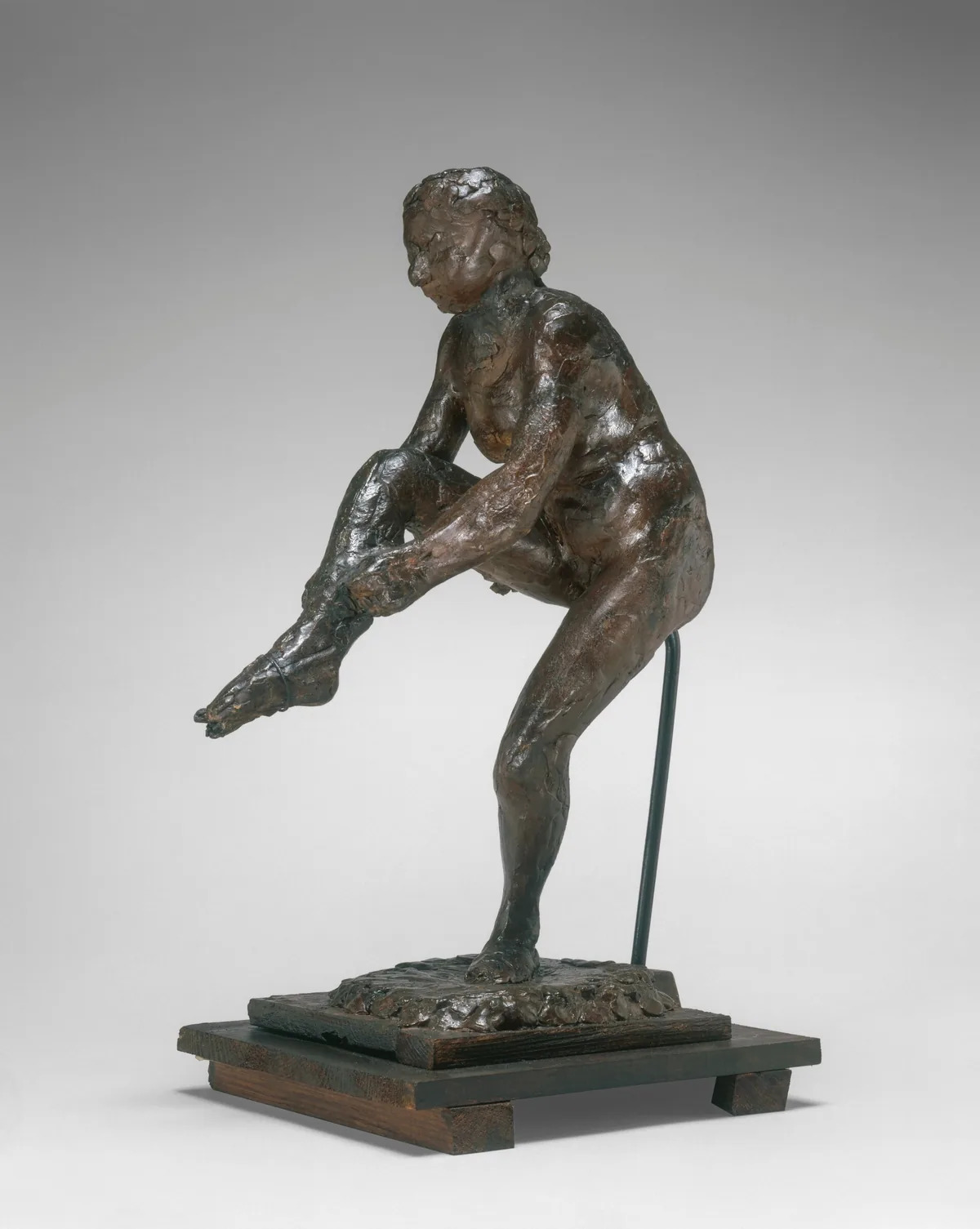 The sculpture shows a figure tying a ribbon around their toes, balanced on one foot.