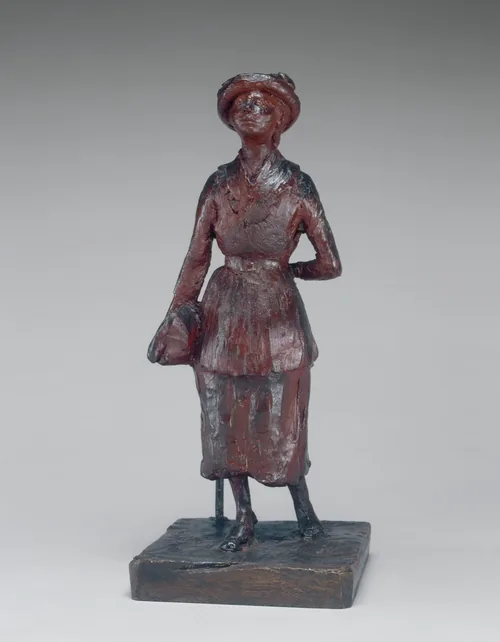 The sculpture depicts a standing figure of a woman dressed in early 20th-century attire.