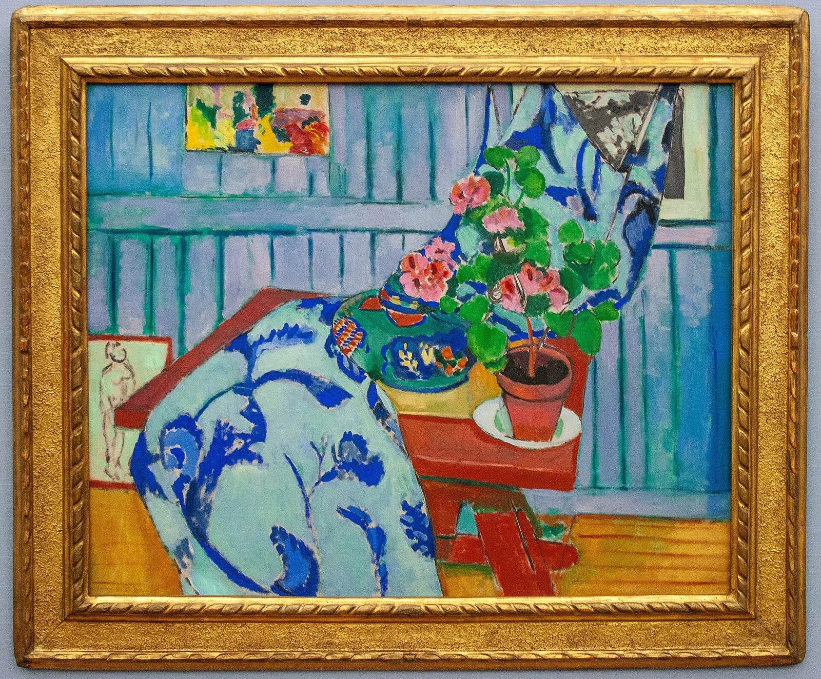 Still life of geranium plant, fruit, water pitcher, and two cats.