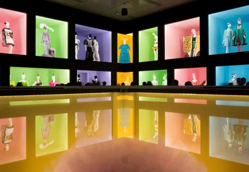 A pink gallery of the Camp: Notes on Fashion exhibition, mannequins in vitrines under a gilded cornice.