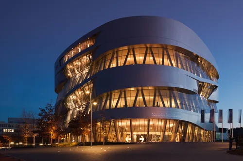 The double-helix volume of the Mercedes-Benz Museum lit from within at blue hour.