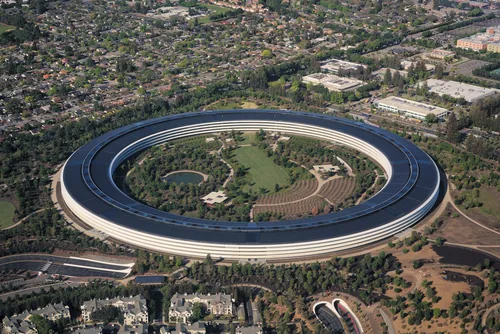 The continuous glass ring of Apple Park seen from the air, enclosing a planted courtyard.