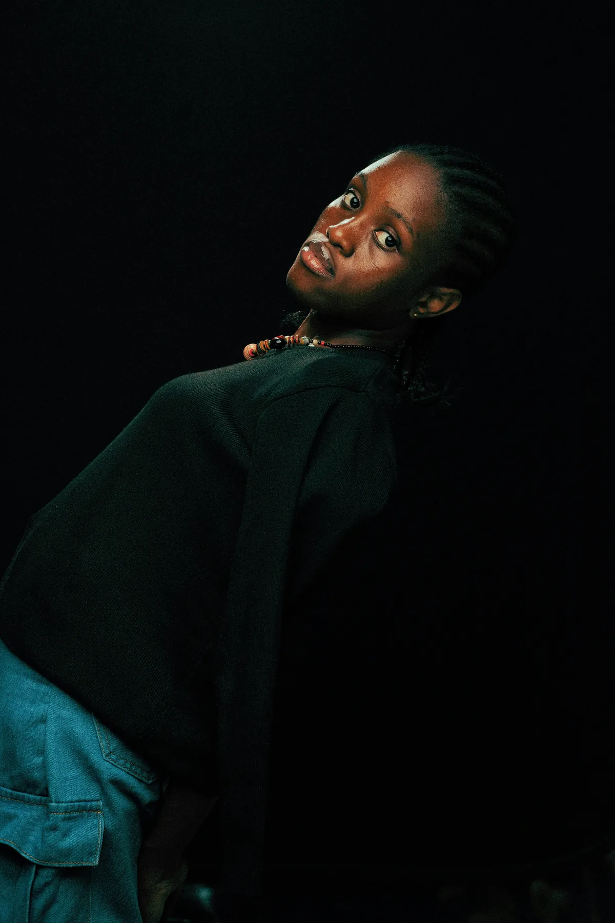 A portrait lit from one side, the sitter turning to look back over a dark shoulder.