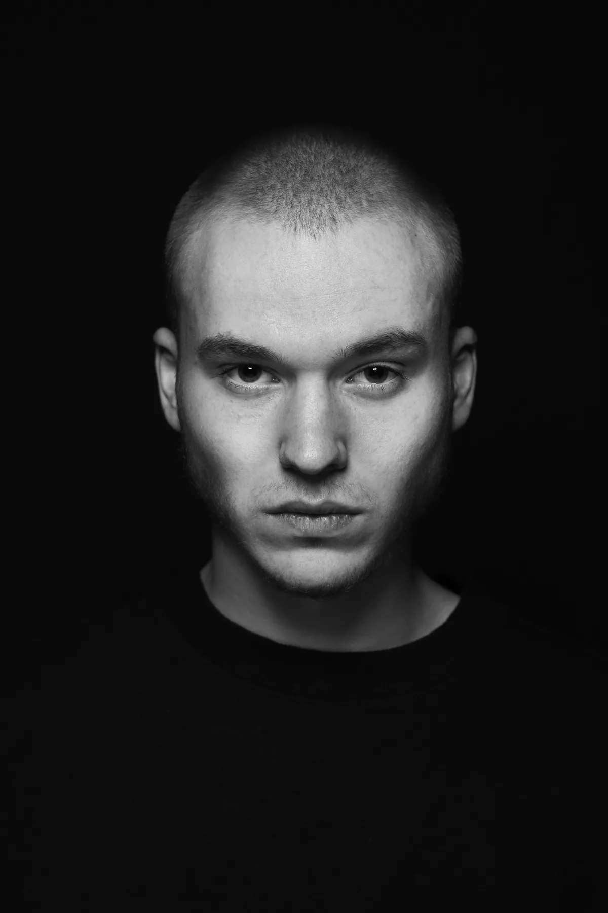 A close, symmetrical black-and-white portrait, lit flat and looking straight into the lens.