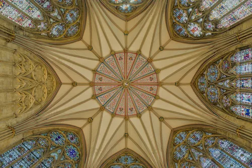 Looking straight up into the star-shaped timber vault of the chapter house at York Minster, ringed by stained glass.