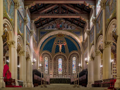 The choir of Reggio Calabria cathedral: gilded coffered ceiling, mosaic apse and a crucifix above the altar.