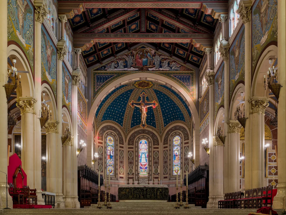 The choir of Reggio Calabria cathedral: gilded coffered ceiling, mosaic apse and a crucifix above the altar.