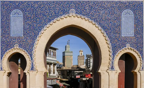 The blue-tiled horseshoe arch of Bab Bou Jeloud framing the minaret of the Bou Inania madrasa.