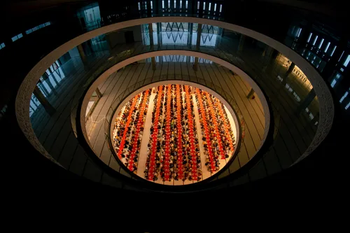 Seen from the gallery above, long rows of worshippers break the Ramadan fast on a round floor under a ring of balconies.