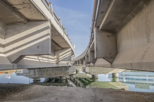Two concrete highway decks running side by side over still water, photographed from underneath.