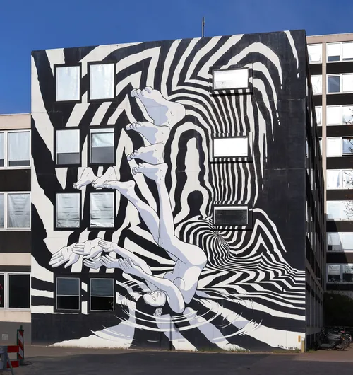 A black-and-white op-art mural of swirling stripes wrapping around an office block.