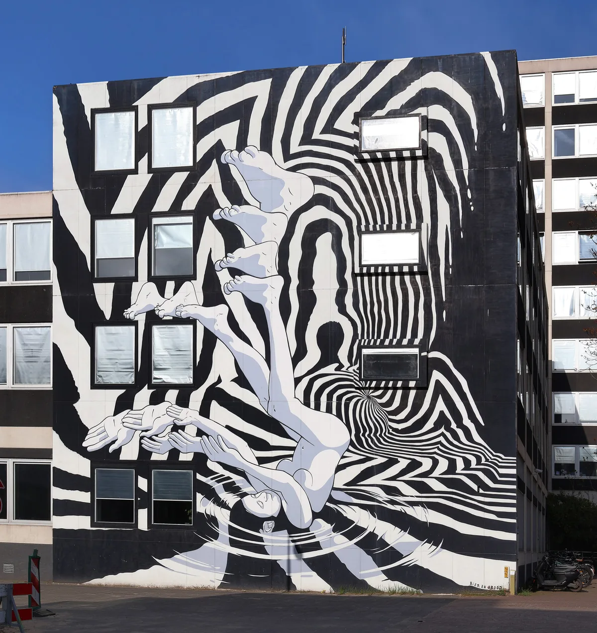 A black-and-white op-art mural of swirling stripes wrapping around an office block.
