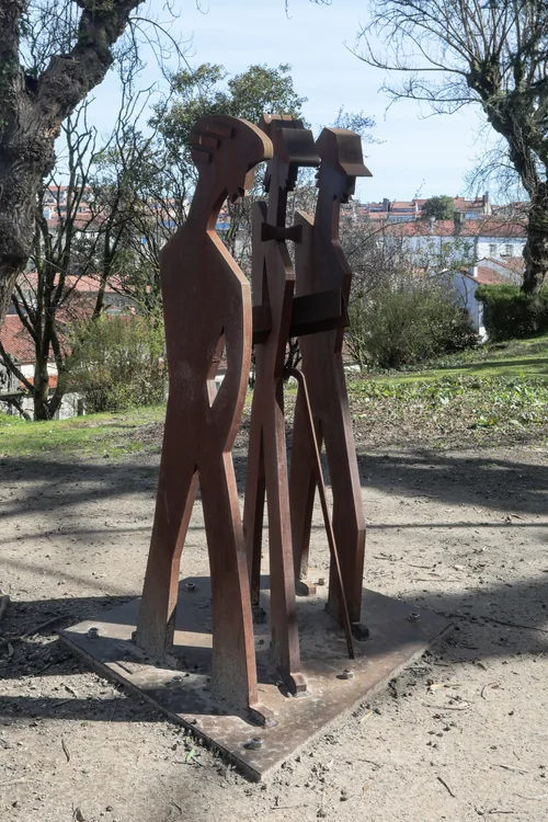 Flat rusted-steel silhouettes of figures standing together in a park.