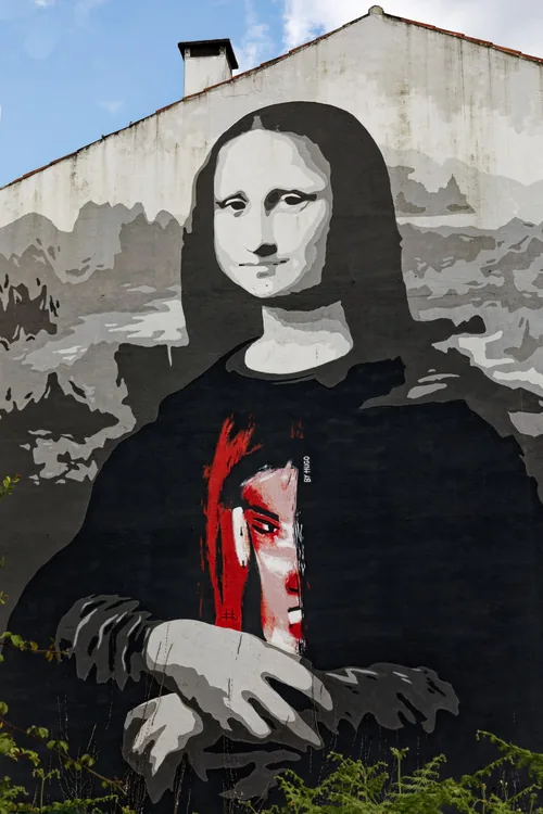A black-and-white Mona Lisa painted on a gable, dressed in a T-shirt with a red and white face.